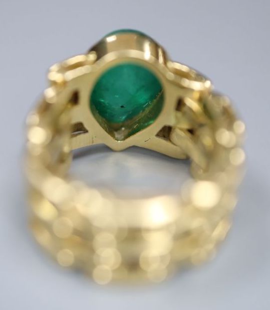 A yellow metal and solitaire pear shaped cabochon emerald set ring, with articulated shank, size G/H, gross 9 grams,
